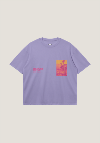 Produktfoto mit Link: Flatlay-Aufnahme eines lilanen Oversize-T-Shirts vor neutralem beigen Hintergrund. Auf der linken Brust-Seite ist ein verfremdeter Kaktus in Gelb und Pink zu sehen (Viereck). Auf der anderen Seite sieht man die Koordinaten des Ortes in Pink. Produkt namens 